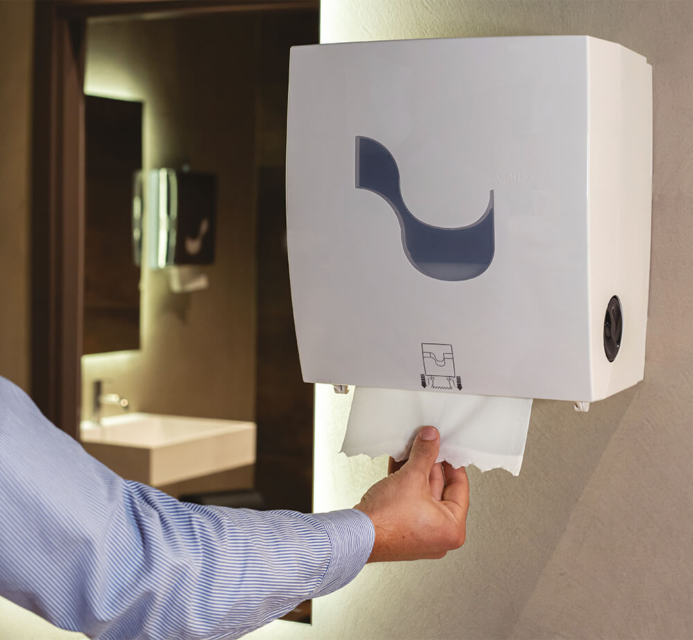 Dispenser da parete Celtex con mano che preleva carta in un bagno moderno