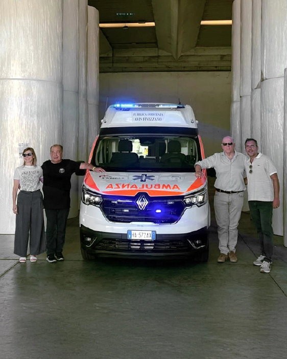 Ambulanza con allestimento donato da Industrie Celtex alla Pubblica assistenza Avis di Fivizzano. Quattro persone sono in piedi davanti al veicolo, dentro la cartiera di San Lorenzo.